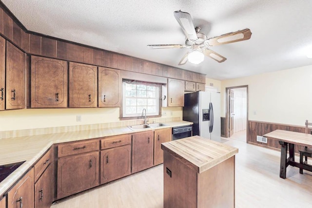 kitchen with dishwasher, sink, stainless steel fridge with ice dispenser, a textured ceiling, and wooden walls