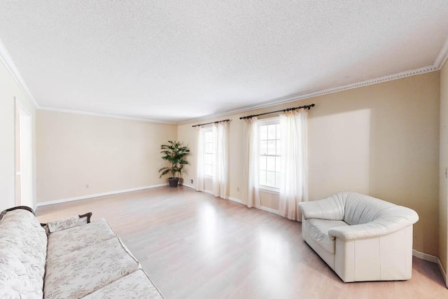 living room featuring light wood-type flooring, a textured ceiling, and ornamental molding