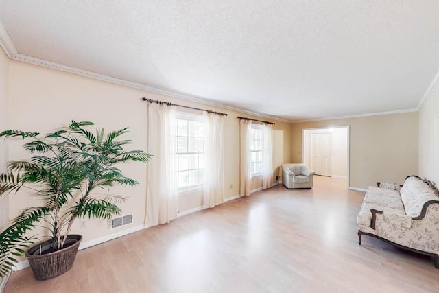 sitting room featuring a textured ceiling, light hardwood / wood-style floors, and crown molding