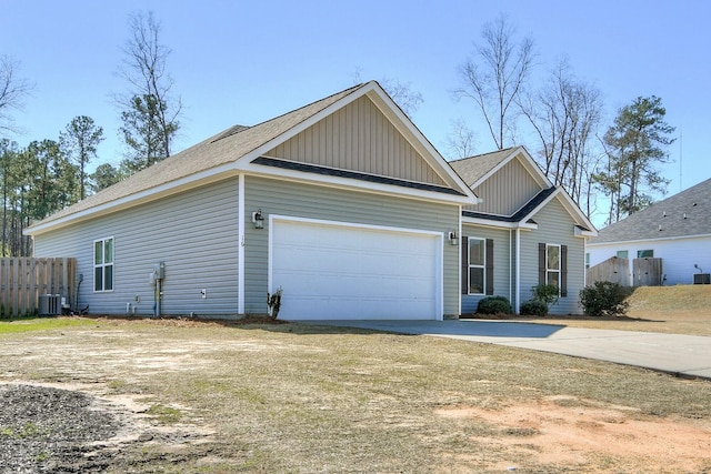 view of front of property featuring central AC unit, an attached garage, concrete driveway, and fence