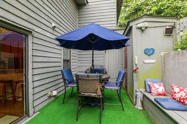 view of patio with fence, a storage shed, an outbuilding, and outdoor dining area