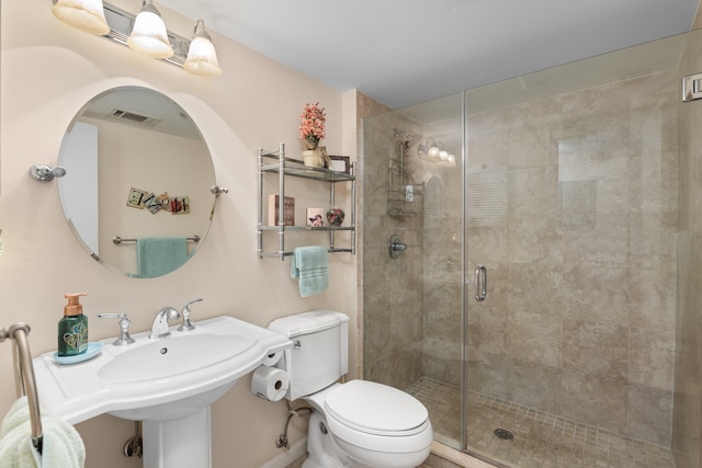 bathroom featuring toilet, a sink, visible vents, and a shower stall