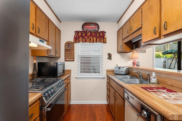 kitchen featuring appliances with stainless steel finishes, under cabinet range hood, brown cabinets, wooden counters, and dark wood-style flooring