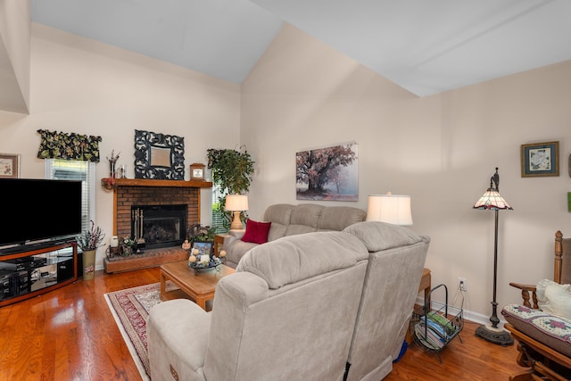 living area with baseboards, high vaulted ceiling, wood finished floors, and a brick fireplace
