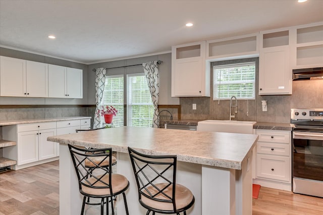 1711 Carolyn Lake Cir, Thomson, GA 30824 - kitchen featuring stainless steel range with electric stovetop, plenty of natural light, a breakfast bar, light wood finished floors, and recessed lighting