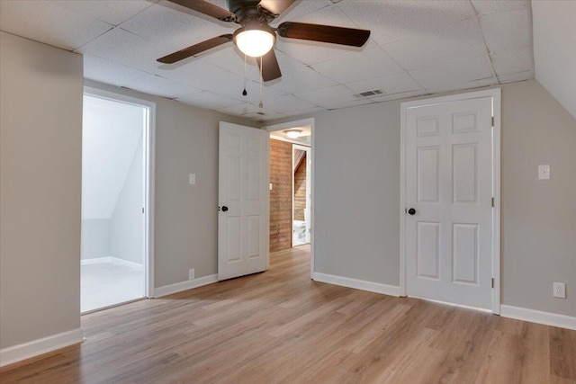 spare room with ceiling fan, a drop ceiling, and light hardwood / wood-style flooring