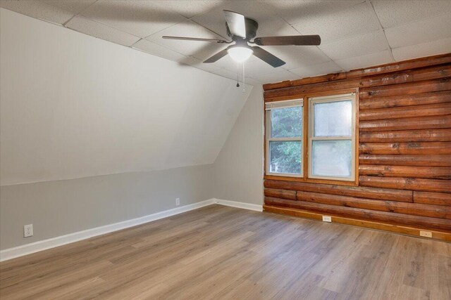 additional living space featuring ceiling fan, log walls, and light wood-type flooring