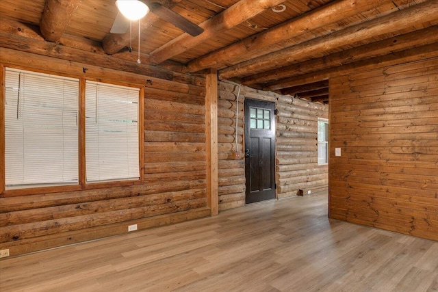 unfurnished room featuring light hardwood / wood-style flooring, ceiling fan, rustic walls, beamed ceiling, and wood ceiling