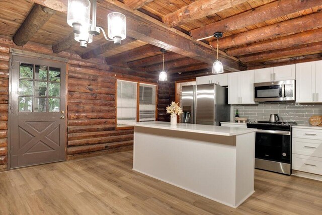 kitchen with hanging light fixtures, white cabinetry, rustic walls, and appliances with stainless steel finishes