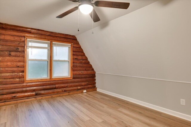 additional living space with rustic walls, ceiling fan, light hardwood / wood-style floors, and vaulted ceiling