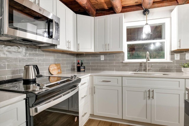 kitchen featuring wooden ceiling, white cabinets, sink, appliances with stainless steel finishes, and beam ceiling