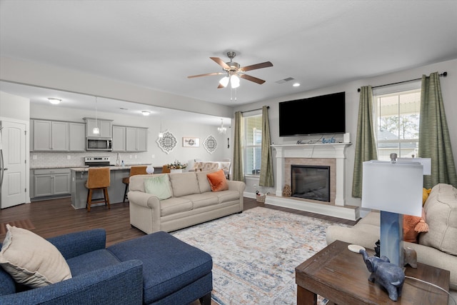 living room featuring ceiling fan, dark hardwood / wood-style flooring, and a fireplace