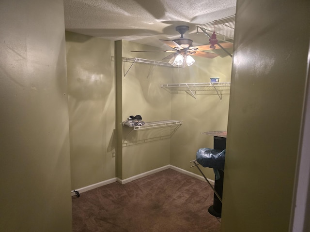 walk in closet with ceiling fan and dark colored carpet