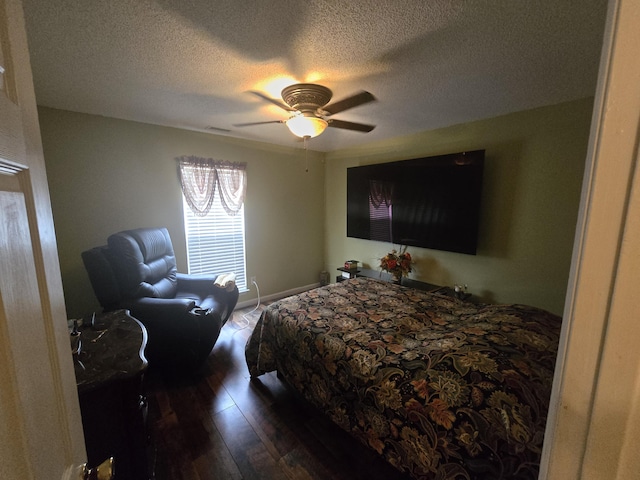 bedroom with a textured ceiling, ceiling fan, and dark wood-type flooring