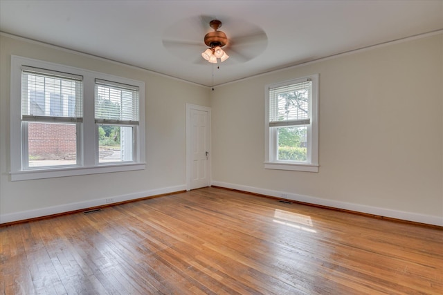 empty room with light wood-type flooring, ornamental molding, a ceiling fan, and baseboards
