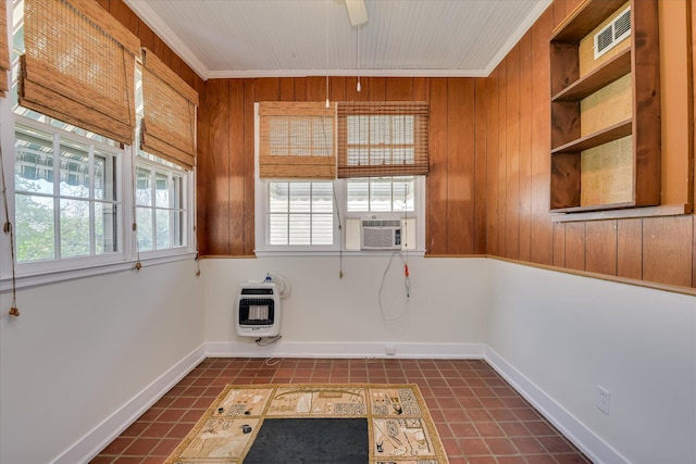 unfurnished room featuring heating unit, cooling unit, wood walls, crown molding, and baseboards