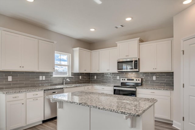 1282 Elias Sta, Thomson, GA 30824 - kitchen with appliances with stainless steel finishes, wood finished floors, white cabinets, a kitchen island, and recessed lighting