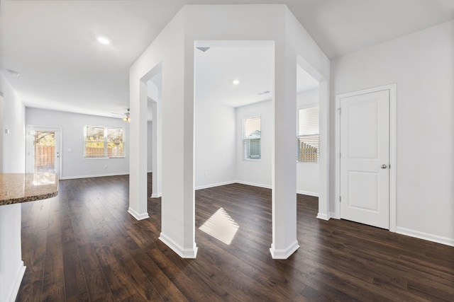 interior space featuring decorative columns, dark wood-type flooring, ceiling fan, and plenty of natural light