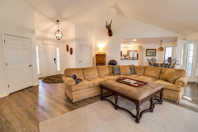 living room with hardwood / wood-style floors, an inviting chandelier, and high vaulted ceiling