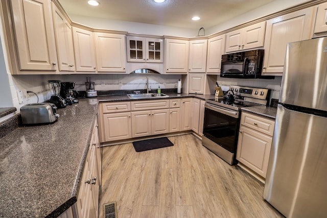 kitchen featuring appliances with stainless steel finishes, tasteful backsplash, light hardwood / wood-style flooring, and sink