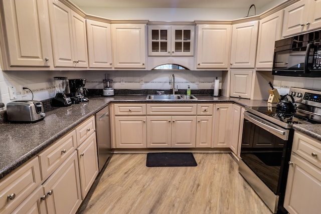 kitchen featuring appliances with stainless steel finishes, light wood-type flooring, backsplash, and sink