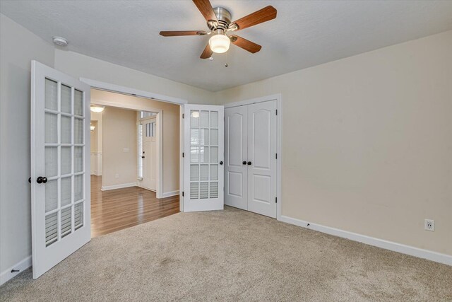 unfurnished bedroom with ceiling fan, carpet, a textured ceiling, french doors, and a closet