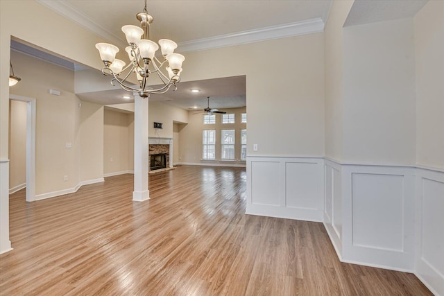 unfurnished living room featuring crown molding, ceiling fan with notable chandelier, and light hardwood / wood-style floors