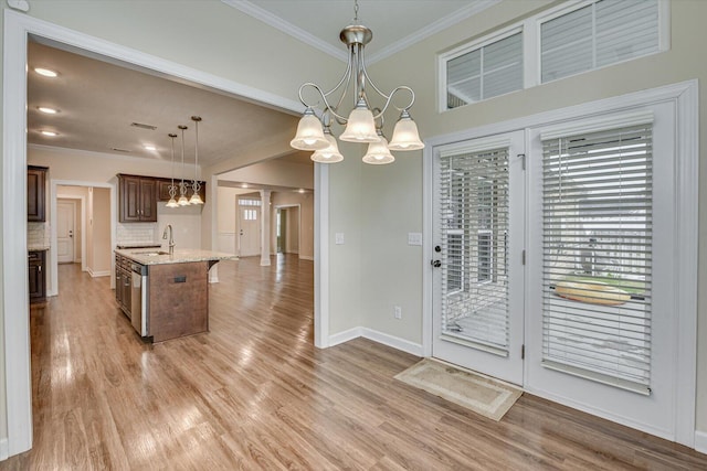 kitchen featuring sink, a chandelier, a kitchen island with sink, and hanging light fixtures