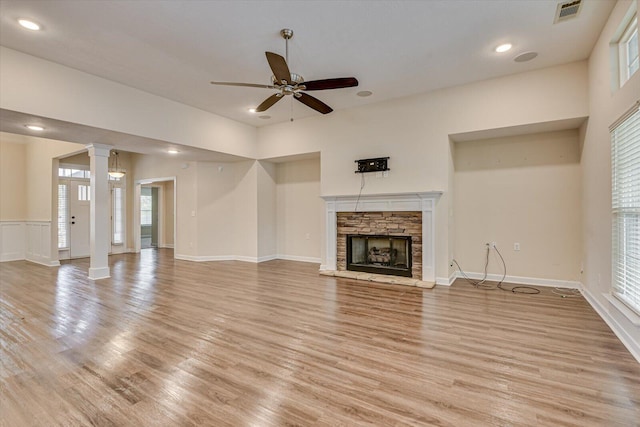 unfurnished living room with decorative columns, ceiling fan, a fireplace, and light hardwood / wood-style flooring