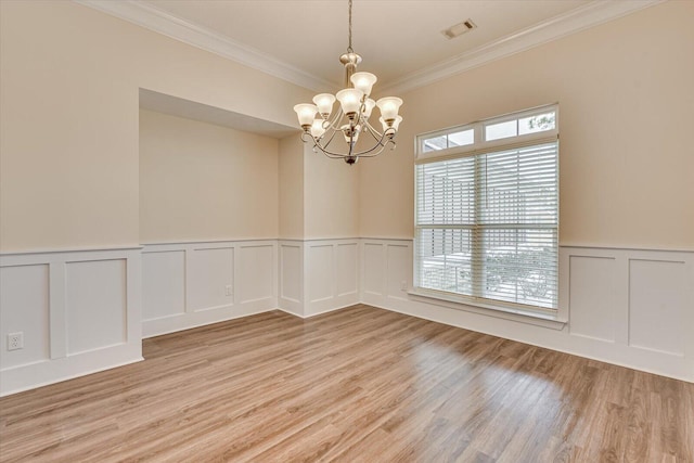 empty room with an inviting chandelier, crown molding, and light hardwood / wood-style floors