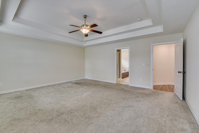 empty room featuring light carpet, ceiling fan, and a tray ceiling