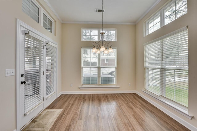 unfurnished dining area featuring a notable chandelier, ornamental molding, and light wood-type flooring