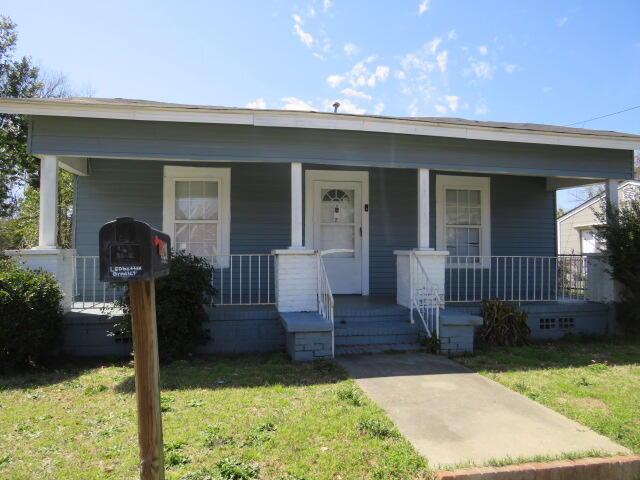 bungalow-style home featuring covered porch and a front yard