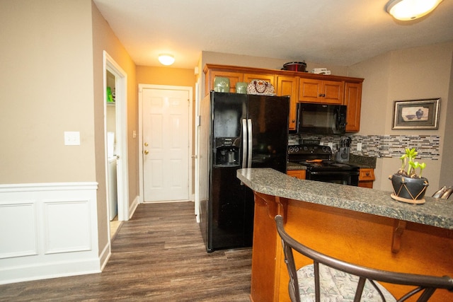 3107 Camden Way, Graniteville, SC 29829 - kitchen featuring black appliances, a breakfast bar area, dark wood-style floors, brown cabinetry, and tasteful backsplash