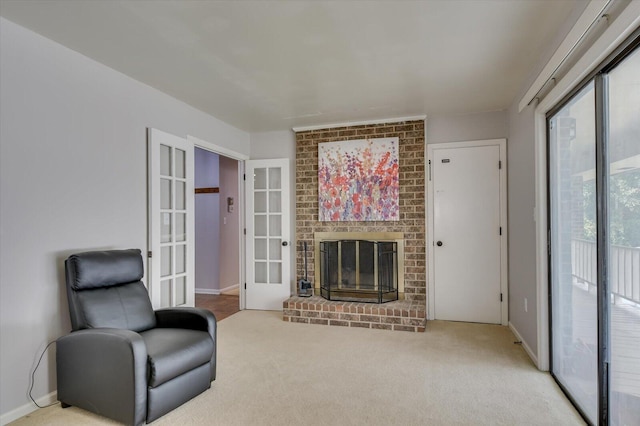 living area with a brick fireplace, carpet flooring, and french doors