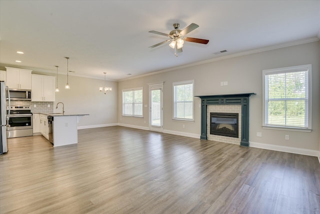 5816 Whispering Pines Way, Evans, GA 30809 - unfurnished living room featuring a fireplace, a chandelier, ceiling fan, crown molding, and wood finished floors