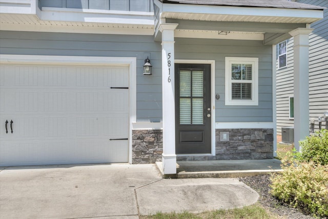 5816 Whispering Pines Way, Evans, GA 30809 - property entrance with stone siding, concrete driveway, covered porch, an attached garage, and central air condition unit