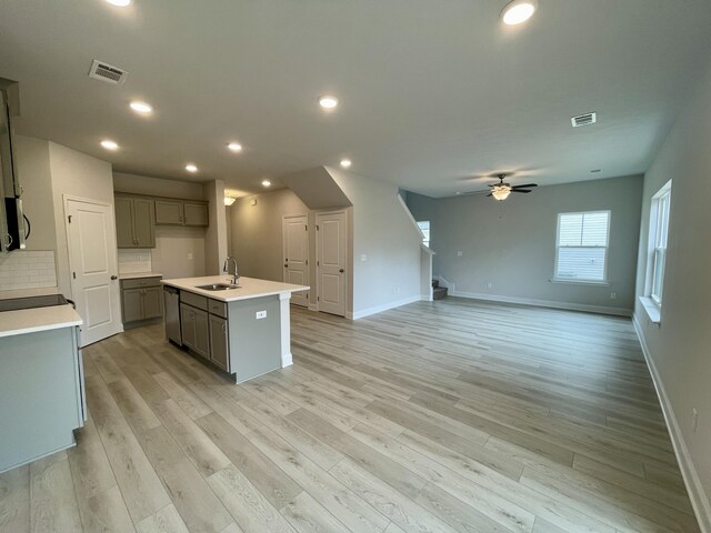 kitchen featuring dishwasher, a center island with sink, sink, ceiling fan, and light hardwood / wood-style floors