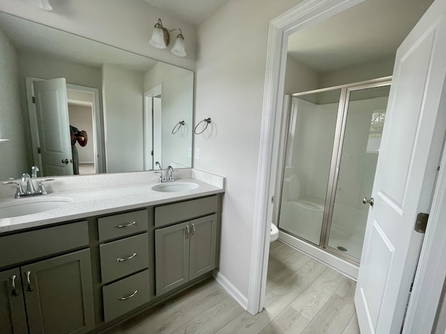 bathroom featuring vanity, wood-type flooring, a shower with shower door, and toilet