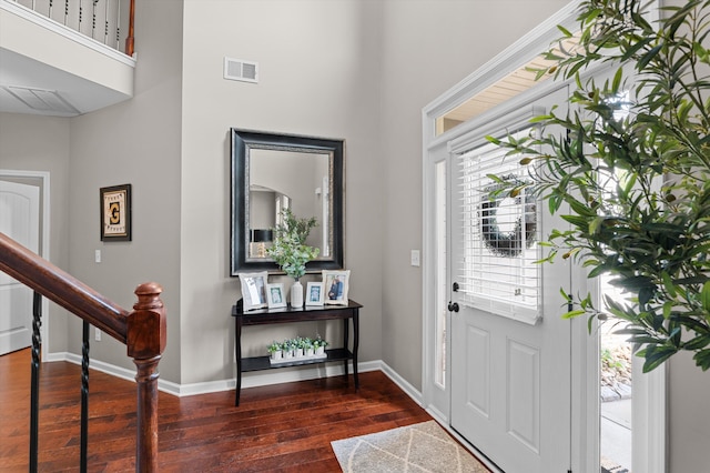 entryway featuring a towering ceiling, dark wood-style floors, baseboards, and stairway