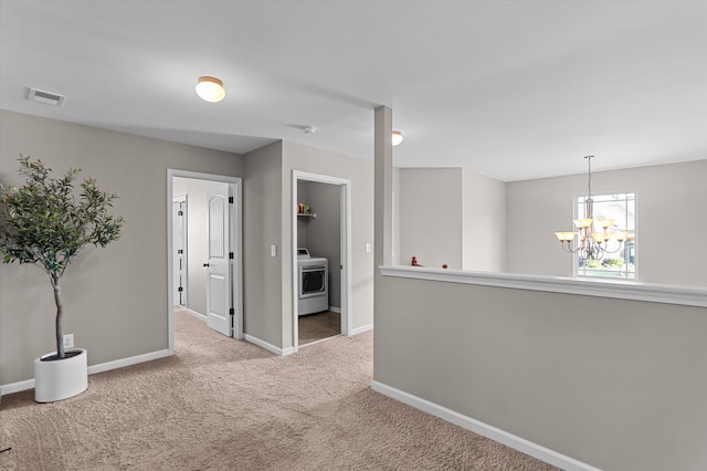 carpeted empty room with washer / clothes dryer, a chandelier, and baseboards