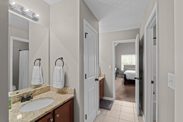 bathroom with vanity, tile patterned flooring, baseboards, and ensuite bath