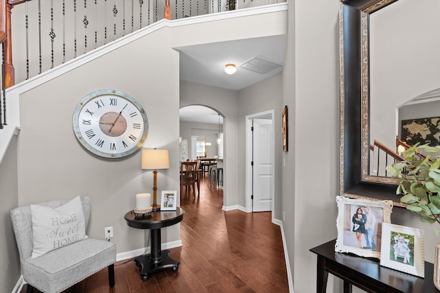 entrance foyer featuring arched walkways, dark wood-type flooring, and baseboards