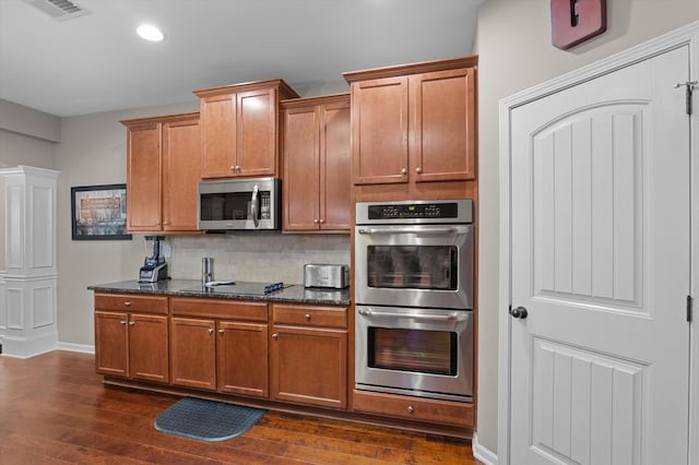 kitchen featuring appliances with stainless steel finishes, recessed lighting, tasteful backsplash, dark wood-style floors, and brown cabinetry