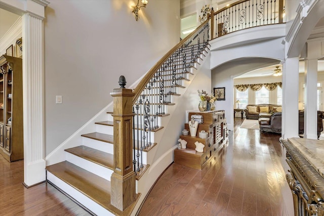 stairway featuring wood-type flooring, decorative columns, and ceiling fan