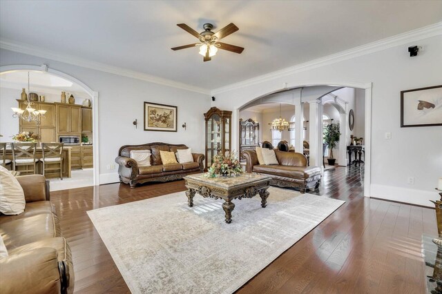 living room featuring ceiling fan with notable chandelier, ornamental molding, and decorative columns