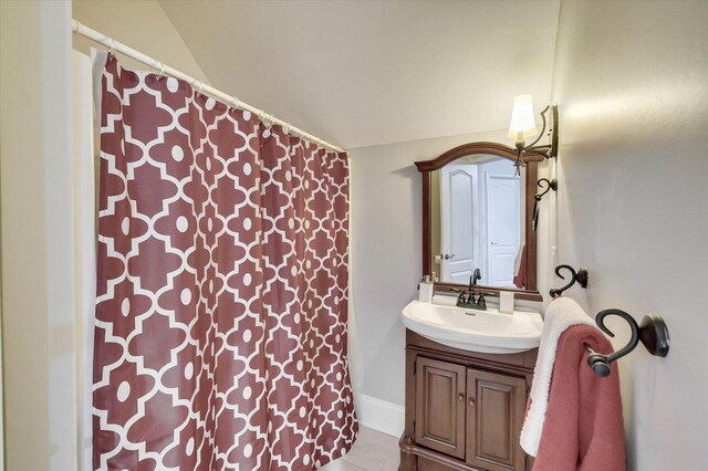 bathroom featuring tile patterned flooring, vanity, and vaulted ceiling