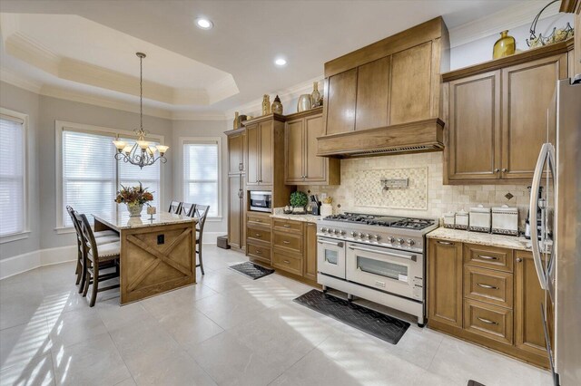 kitchen featuring appliances with stainless steel finishes, a breakfast bar, a tray ceiling, decorative light fixtures, and a center island