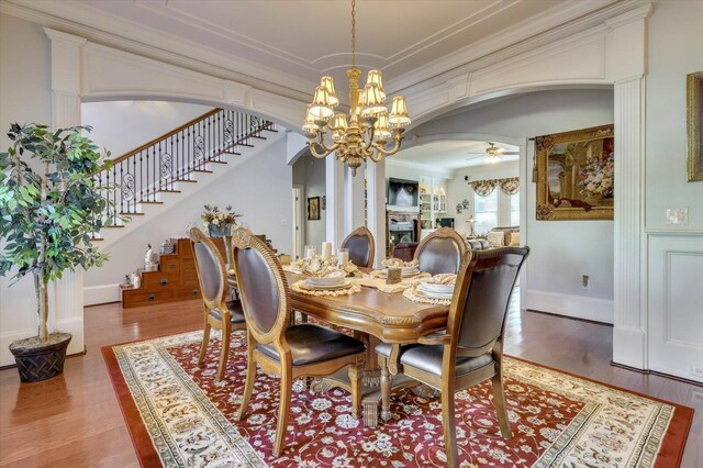 dining area with ceiling fan with notable chandelier, wood-type flooring, and ornamental molding