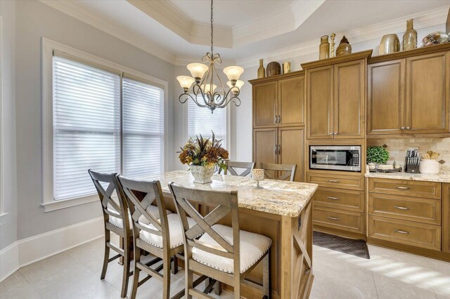 tiled dining area with a chandelier, a tray ceiling, and crown molding